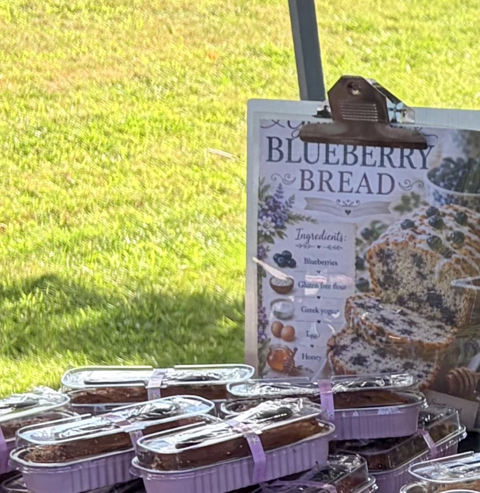Wrapped loaves of gluten-free blueberry bread in front of a Blueberry Bread sign