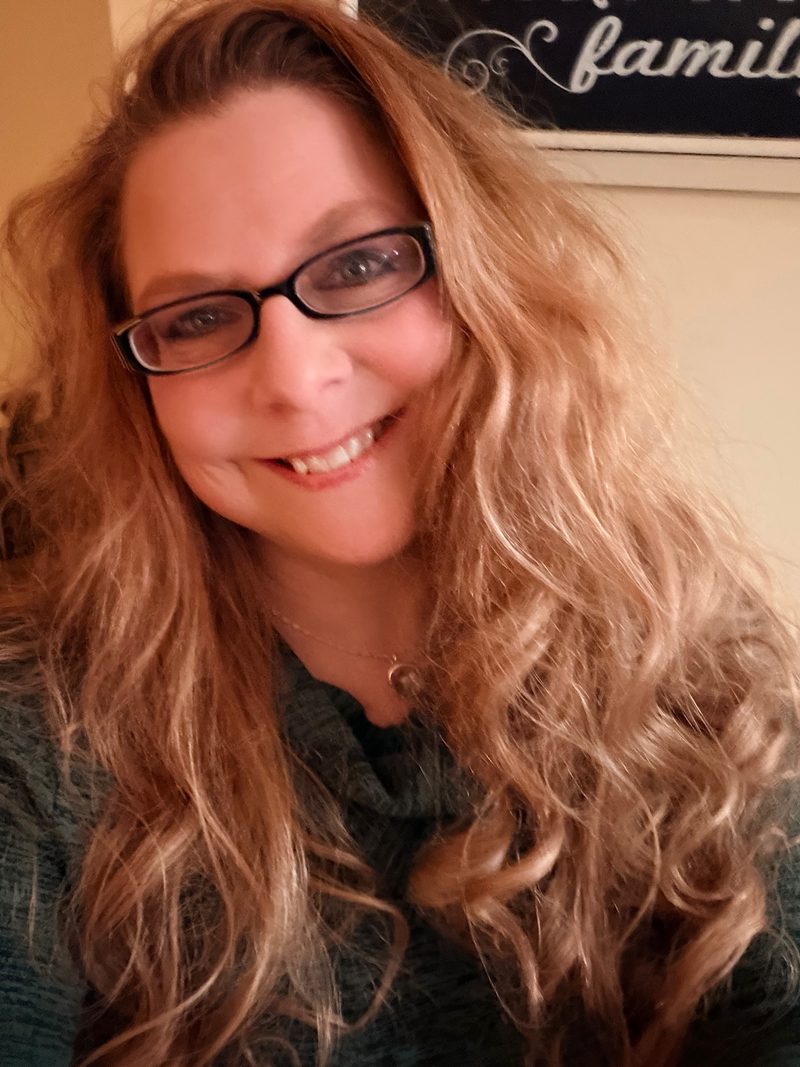 Lisa Holmes smiling, with glasses and long wavy hair